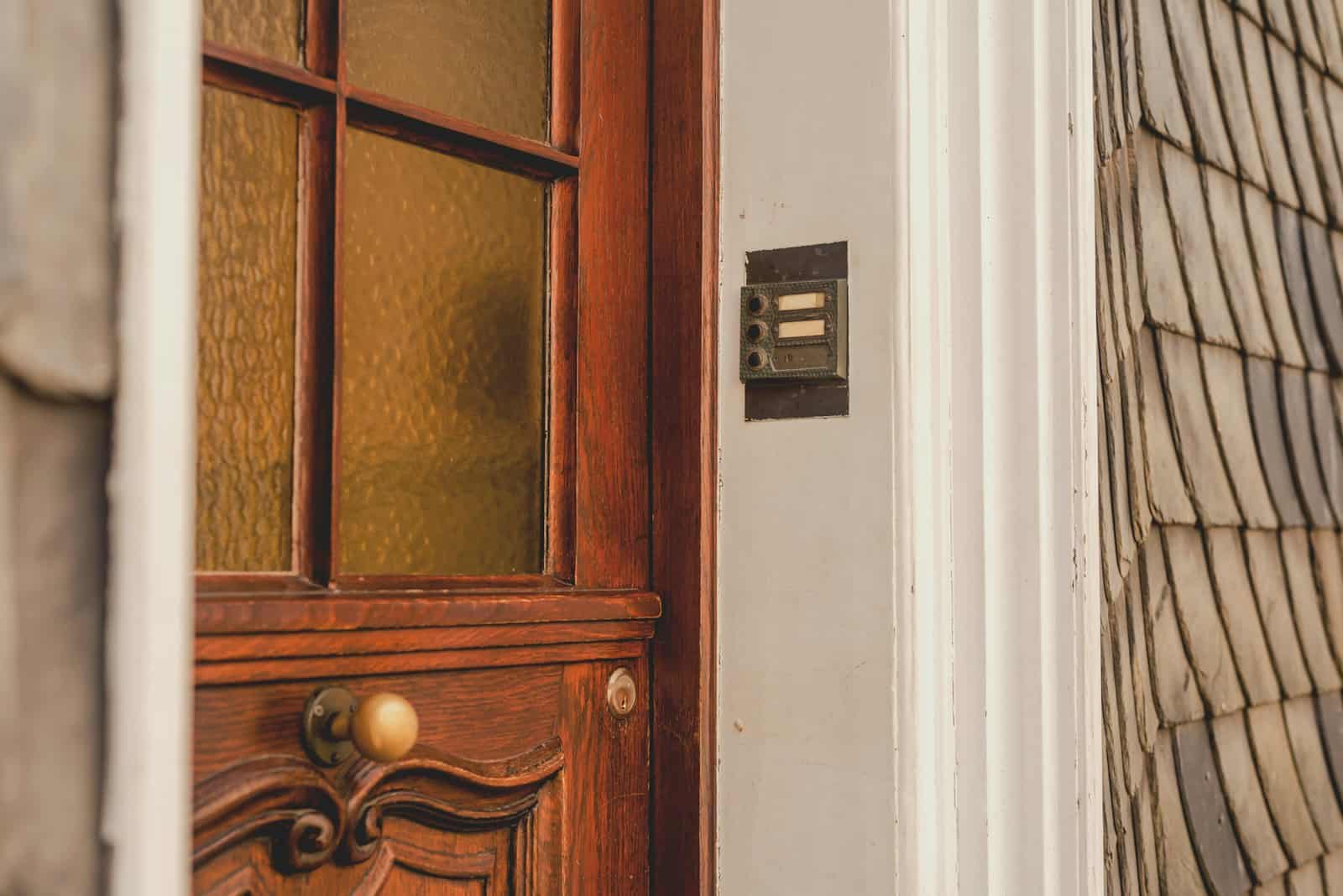 Holzhaustür mit Klingelschild an der Hauswand